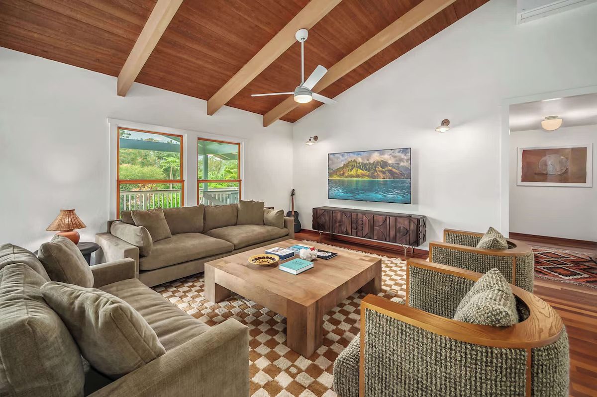 Open living and dining room with vaulted open-beam ceiling, hardwood floors and sliding doors to the lanai.