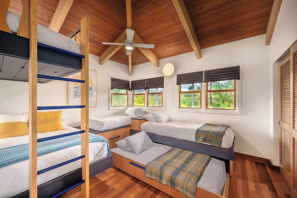 Bunk room with a double bunk and additional twin beds under a vaulted wood ceiling.