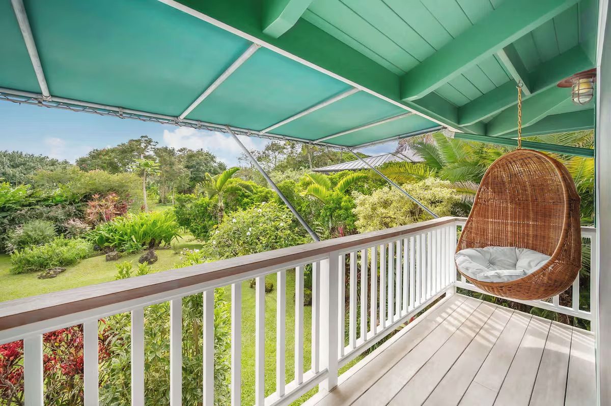 A woven rattan hanging egg chair on the upper lanai, overlooking the garden.