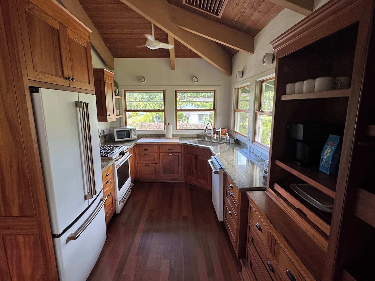 Kitchen with open koa shelving, range and a window over the counter to the garden.