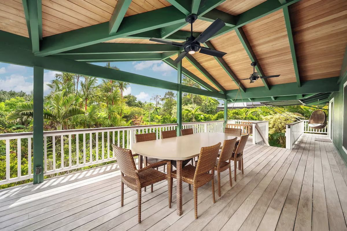 The full length of the covered upper deck, dining table set beneath the open-beam ceiling.